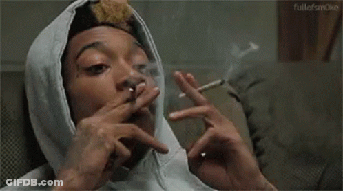 A Man Wearing A Hoodie Is Smoking A Cigarette . GIF