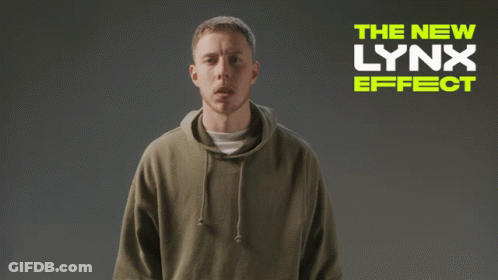 A Man Wearing A Hoodie Is Standing In Front Of A Sign That Says The New Lynx Effect GIF