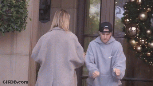 A Man Wearing A Hoodie That Says ' Justin Bieber ' On It Is Standing Next To A Woman GIF