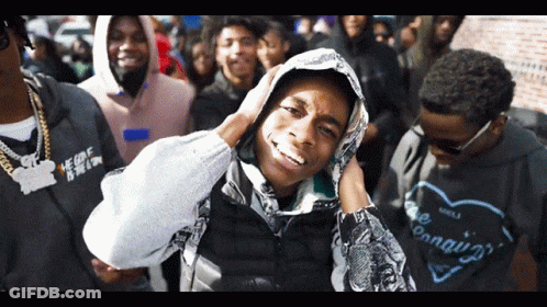 A Man Wearing A Hoodie With The Word Conquer On It Stands In A Crowd GIF