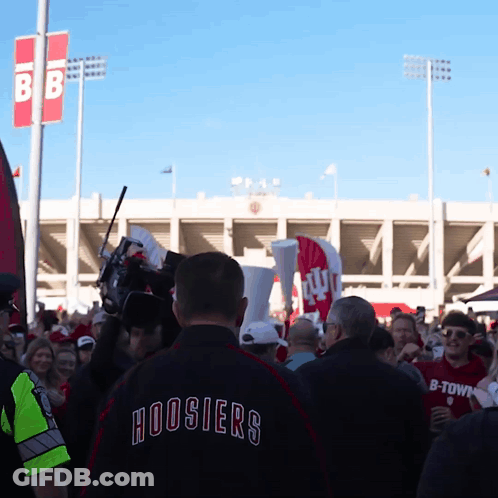A Man Wearing A Hoosier 'S Jacket Stands In A Crowd Of People GIF