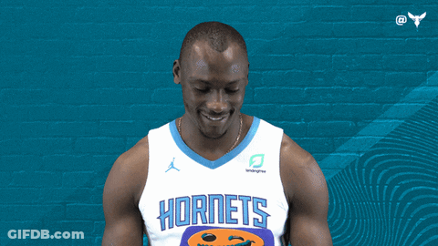 A Man Wearing A Hornets Jersey Smiles In Front Of A Blue Wall GIF