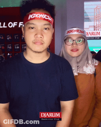 A Man Wearing A Indonesia Headband Is Standing Next To A Woman Wearing Glasses GIF