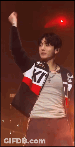A Man Wearing A Jacket That Says Kt Is Raising His Fist In The Air GIF