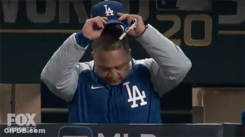 A Man Wearing A Jacket That Says La Is Sitting In Front Of A Scoreboard GIF