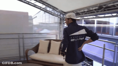 A Man Wearing A Jacket That Says Scuderia On The Back Is Standing On A Balcony GIF