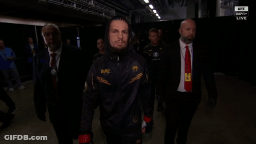 A Man Wearing A Jacket That Says Ufc Is Walking In A Dark Room GIF