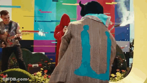 A Man Wearing A Jacket With The Number 11 On It Is Standing In Front Of A Colorful Wall . GIF