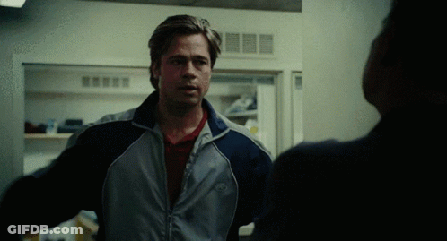 A Man Wearing A Jacket With The Word Nike On It Stands In Front Of A Refrigerator GIF