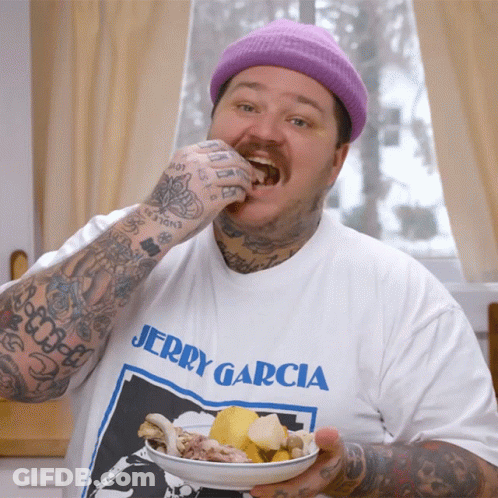 A Man Wearing A Jerry Garcia T-Shirt Is Eating Food From A Plate GIF