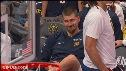 A Man Wearing A Jersey That Says / Botta Sits In A Basketball Hoop GIF