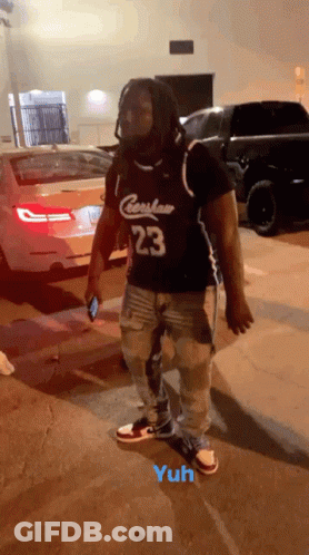 A Man Wearing A Jersey With The Number 23 On It Is Standing In A Parking Lot GIF