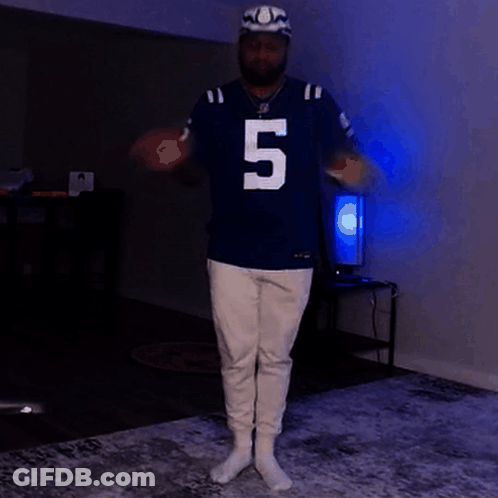 A Man Wearing A Jersey With The Number 5 On It Is Standing In A Dark Room GIF
