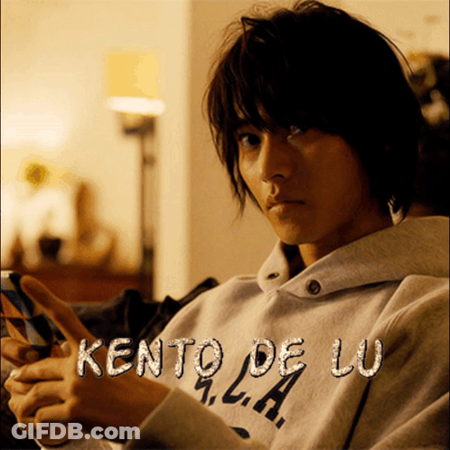 A Man Wearing A Kento De Lu Sweatshirt Is Holding A Cell Phone GIF