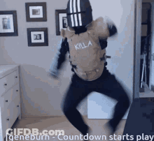 A Man Wearing A Killa Vest Is Dancing In A Room GIF