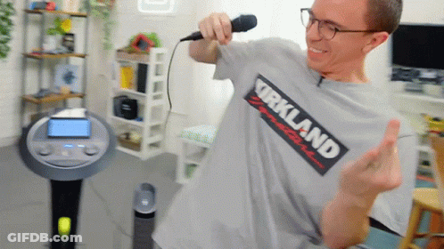 A Man Wearing A Kirkland T-Shirt Sings Into A Microphone GIF