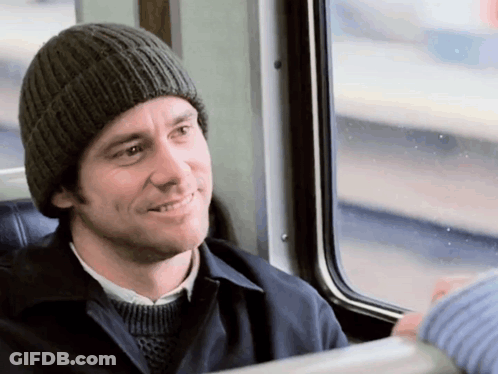 A Man Wearing A Knitted Hat Is Smiling While Sitting On A Train GIF