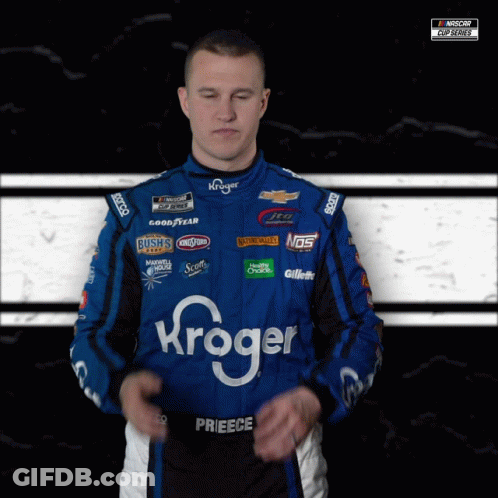 A Man Wearing A Kroger Racing Suit Stands With His Eyes Closed GIF
