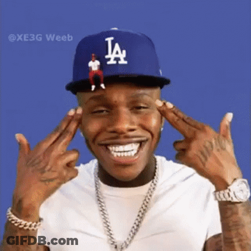 A Man Wearing A La Hat And A White Shirt Is Making A Peace Sign . GIF