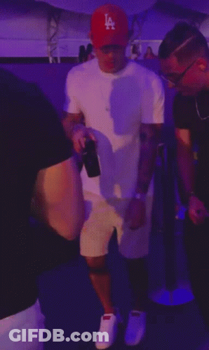 A Man Wearing A La Hat Is Dancing With Another Man GIF