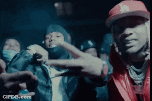 A Man Wearing A La Hat Is Giving A Peace Sign GIF