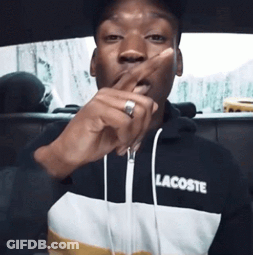 A Man Wearing A Lacoste Sweatshirt Is Covering His Mouth With His Hand GIF