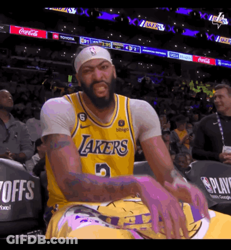 A Man Wearing A Lakers Jersey Is Sitting In The Stands GIF
