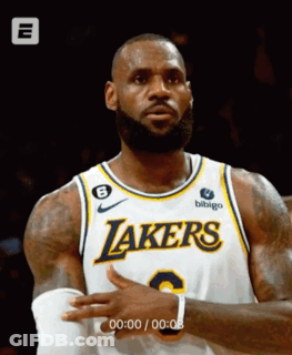A Man Wearing A Lakers Jersey Is Standing In Front Of A Black Background GIF