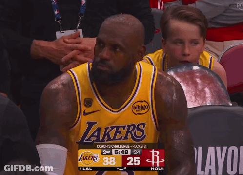 A Man Wearing A Lakers Jersey Sits In A Stadium GIF