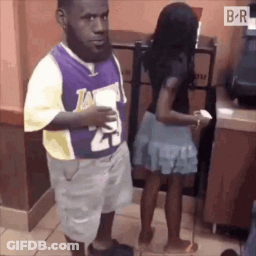 A Man Wearing A Lakers Jersey Stands Next To A Woman GIF