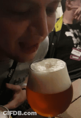 A Man Wearing A Lanyard That Says ' Ncs ' On It Looks At A Glass Of Beer GIF