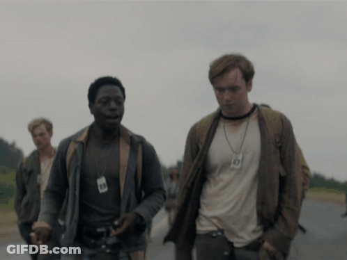 A Man Wearing A Lanyard With The Number 49 On It Walks Down A Road GIF