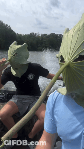A Man Wearing A Leaf Mask Is Sitting On A Boat Next To Another Man GIF