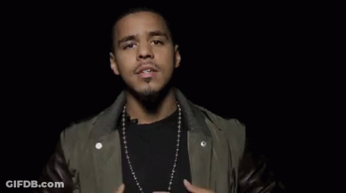A Man Wearing A Leather Jacket And A Necklace Is Making A Funny Face With His Hands In The Air . GIF