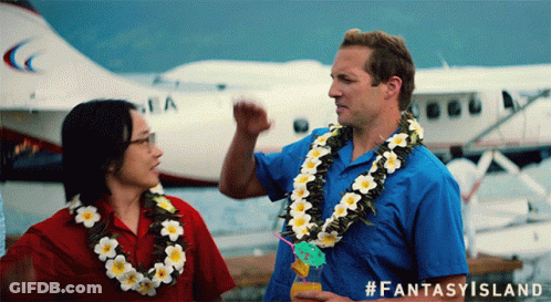 A Man Wearing A Lei Stands Next To A Woman Wearing A Lei And A Plane In The Background GIF