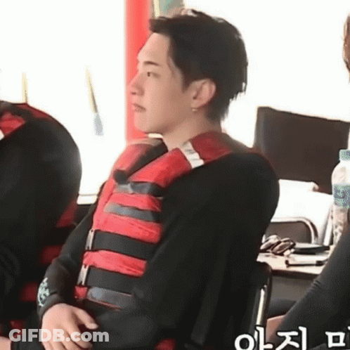 A Man Wearing A Life Jacket Is Sitting On A Chair . GIF