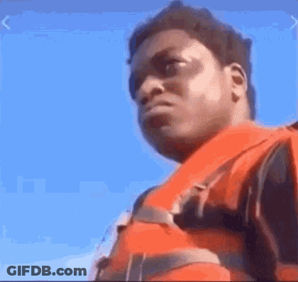 A Man Wearing A Life Jacket Is Standing On A Boat . GIF