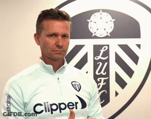 A Man Wearing A Light Blue Clipper Shirt Stands In Front Of A Logo GIF