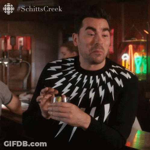 A Man Wearing A Lightning Bolt Sweater Holds A Glass GIF