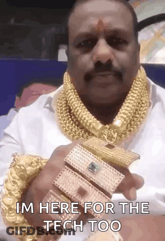 A Man Wearing A Lot Of Gold Jewelry Is Holding A Bracelet That Says I 'M Here For The Tech Too . GIF