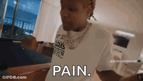 A Man Wearing A Louis Vuitton Shirt Is Standing In A Living Room And Says `` Pain '' . GIF