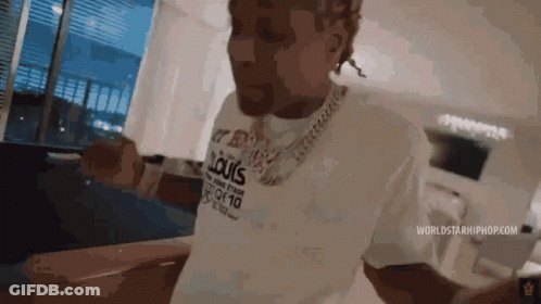 A Man Wearing A Louis Vuitton Shirt Is Standing In A Room . GIF