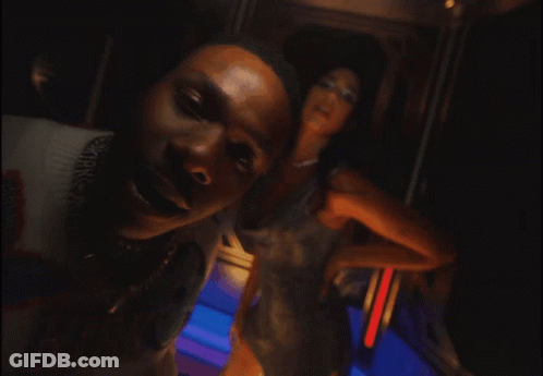 A Man Wearing A Louis Vuitton Sweater Stands Next To A Woman In A Dress GIF
