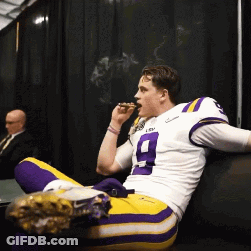 A Man Wearing A Lsu Jersey Is Smoking A Cigar GIF