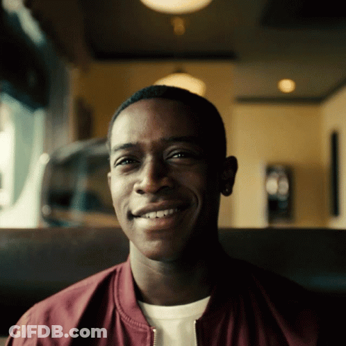 A Man Wearing A Maroon Jacket Is Smiling For The Camera GIF