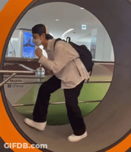 A Man Wearing A Mask And A Backpack Is Walking Through A Tunnel GIF