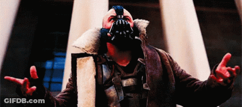A Man Wearing A Mask And A Fur Coat Is Standing In Front Of A Building . GIF