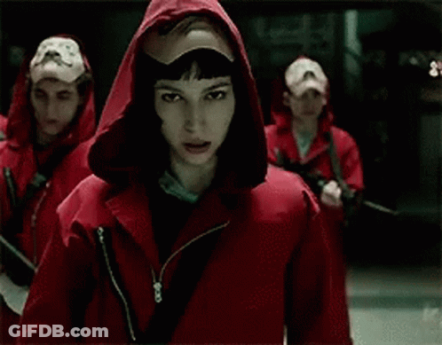 A Man Wearing A Mask And A Hood Is Holding His Hand To His Mouth . GIF