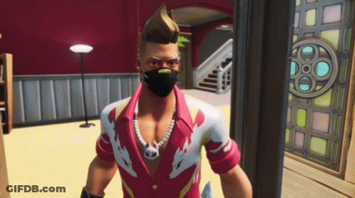 A Man Wearing A Mask And A Necklace Stands In A Room GIF