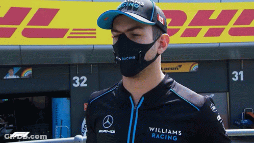 A Man Wearing A Mask And A Williams Racing Shirt Stands In Front Of Dhl GIF